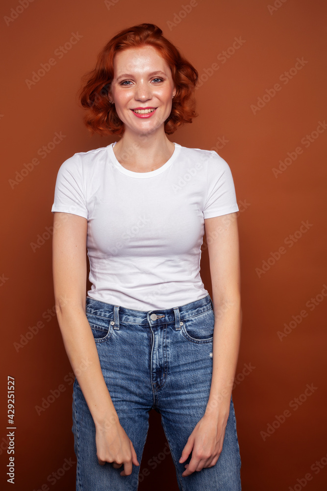 Obraz premium young pretty redhead girl posing cheerful on warm brown background, lifestyle people concept
