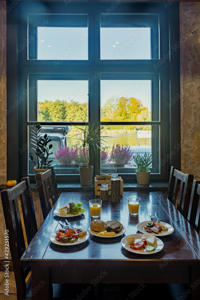 Plates with self-service breakfast on a table in restaurant. Few plates and glasses with orange juice. Plates with self-service breakfast on a table in restaurant. Few plates and glasses with orange juice.