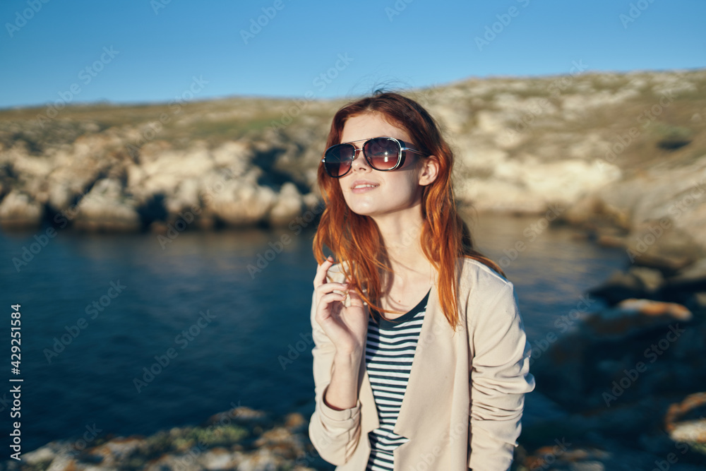 woman t-shirt and sweater on nature in the mountains near the sea glasses on her face woman t-shirt and sweater on nature in the mountains near the sea glasses on her face
