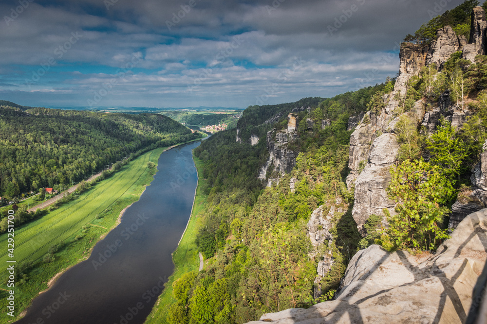 View from viewpoint of Bastei Bridge in Saxon Switzerland Germany to the town at the mountain on a cloudy day