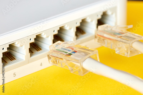 Ethernet cables connected to Desktop Switch or routerboard on a yellow background. Close-up, selective focus photo