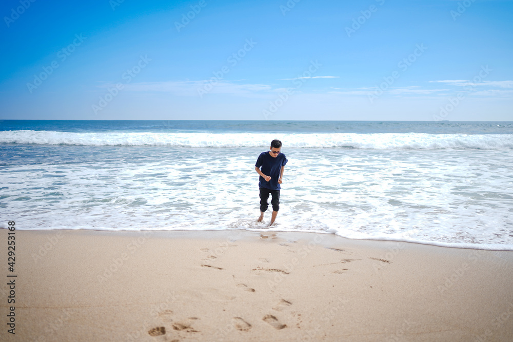 a man in a blue shirt, being chased by the waves. This beach looks beautiful, clean and white sand