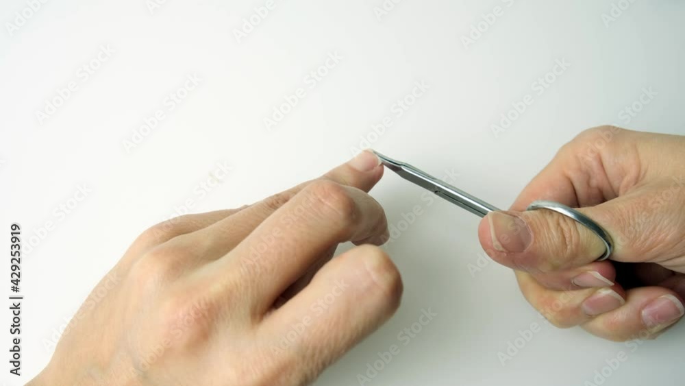 Hand of a woman cutting nails with scissors and making manicure by herself at home Hand of a woman cutting nails with scissors and making manicure by herself at home