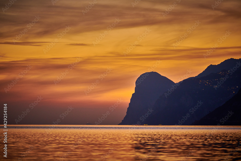View of the beautiful Lake Garda surrounded by mountains, Scenic view of sunset at Lake Garda in the evening with the beautiful sunset colors, italy, Soft focus due to long exposure
