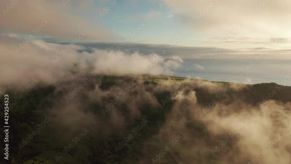 Drone flying among white clouds covered green mountains of Poco Ribeira do Ferreiro, Alagoinha, Flores Island, Azores, Portugal, Europe. Aerial shot of evergreen island of Flores , 4k footage