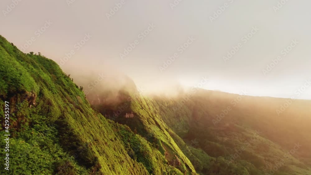 Drone flying along mountains in clouds of Poco Ribeira do Ferreiro, Alagoinha, Flores Island, Azores, Portugal, Europe. Aerial view of cliffs covered green vegetation, 4k footage