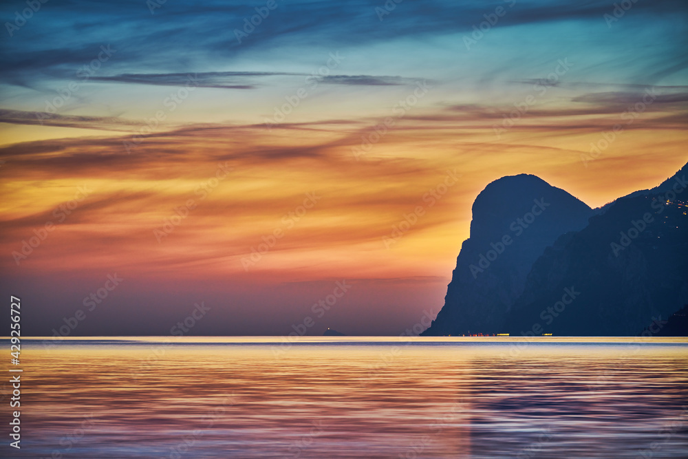 View of the beautiful Lake Garda surrounded by mountains, Scenic view of sunset at Lake Garda in the evening with the beautiful sunset colors, italy, Soft focus due to long exposure View of the beautiful Lake Garda surrounded by mountains, Scenic view of sunset at Lake Garda in the evening with the beautiful sunset colors, italy, Soft focus due to long exposure