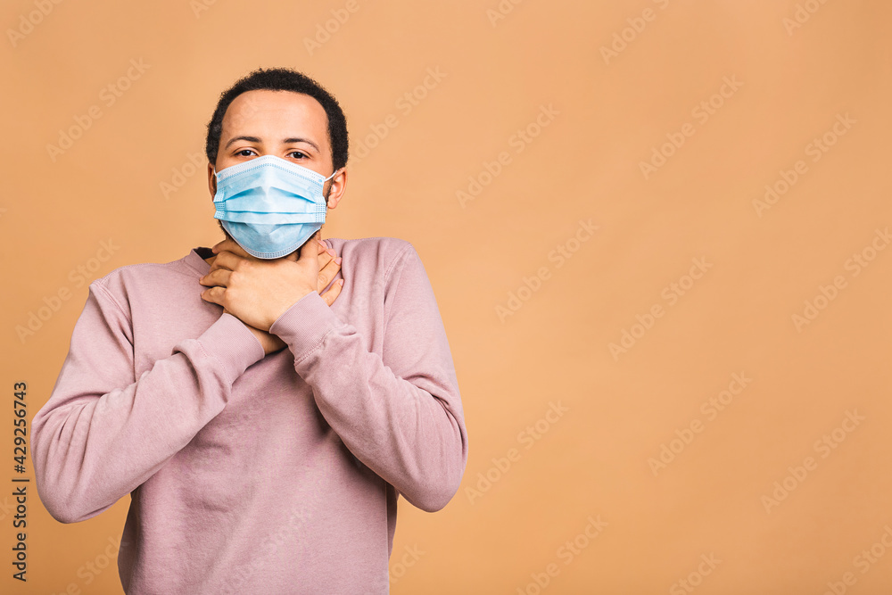 Coronavirus. African american black man wearing hygienic mask to prevent infection, airborne respiratory illness such as flu, 2019-nCoV. Isolated on beige background. Coronavirus. African american black man wearing hygienic mask to prevent infection, airborne respiratory illness such as flu, 2019-nCoV. Isolated on beige background.