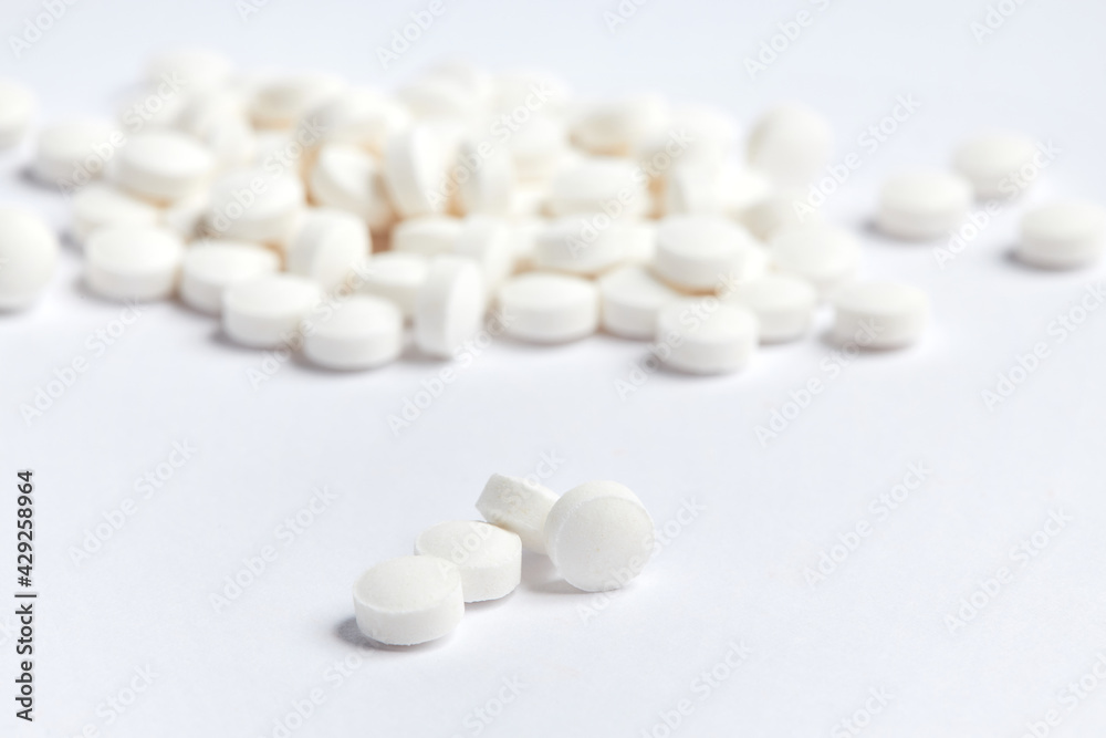 White round pills on a white background. A heap of small round meds. Health care and medicine concept White round pills on a white background. A heap of small round meds. Health care and medicine concept