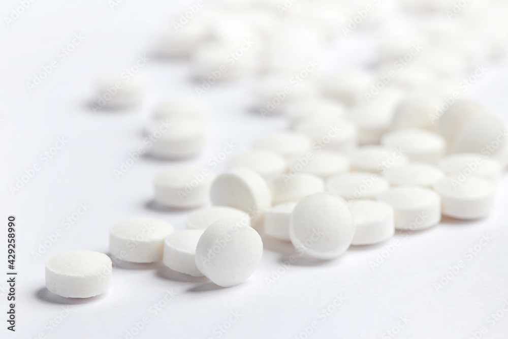White round pills on a white background. A heap of small round meds. Health care and medicine concept White round pills on a white background. A heap of small round meds. Health care and medicine concept