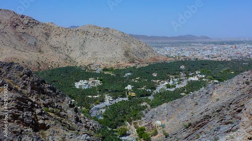 Aerial view of palm fields surrounded by Al Hajar Mountains in Oman