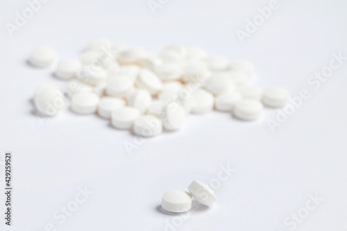 White round pills on a white background. A heap of small round meds. Health care and medicine concept