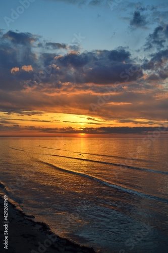 Birds fly low over the water. Seagull on sea. Evening summer scenery view. Colorful clouds on sunset, with beautiful reflection. Baltic Sea in Jurmala resort, Latvia.