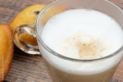 tasse de café au lait et madeleine sur une table