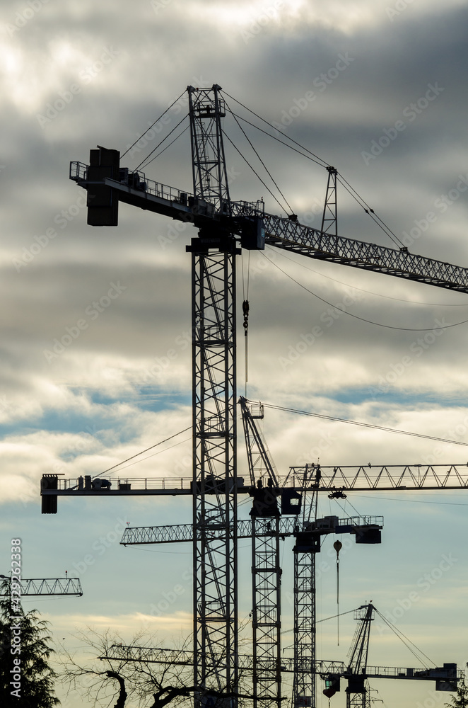 Construction site with cranes at sunset, sunrise, dawn time with the cranes as a silhouette. Vancouver, Canada. Vertical. Construction site with cranes at sunset, sunrise, dawn time with the cranes as a silhouette. Vancouver, Canada. Vertical.