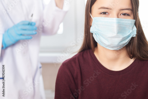 Vaccination of adolescents in medical clinics, schools, a doctor giving an injection to a girl in a hospital, a nurse holding a syringe before administering a dose of vaccine