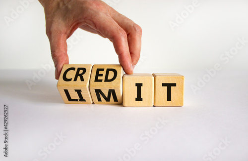 Credit limit symbol. Businessman turns wooden cubes and changes the word 'limit' to 'credit'. Beautiful white table, white background, copy space. Business and credit limit concept.