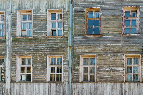 Wall background of old ramshackle wooden house with many windows