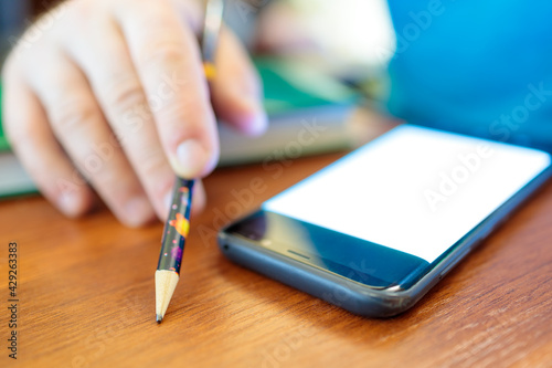 a man holds a pencil in his hand, in front of him lies a smartphone with the screen on, a workflow is in progress