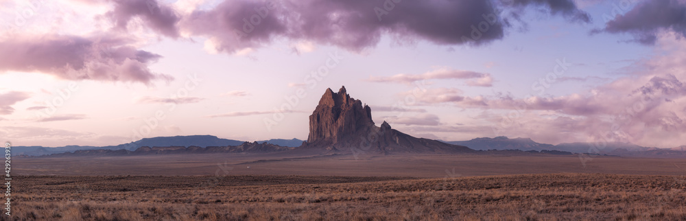 Panoramic American Nature Landscape View of the Dry Desert and Rugged Rocky Mountains. Colorful Sunrise Sky Art Render. Taken at Shiprock, New Mexico, United States.