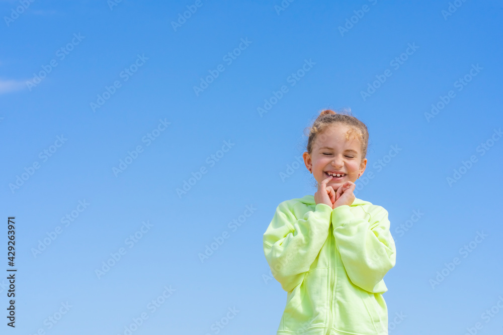 Portrait of beautiful little girl in yellow sweet on a blue sky background. Happiness concept, active childhood, carefree, summer lifestyle. Portrait of beautiful little girl in yellow sweet on a blue sky background. Happiness concept, active childhood, carefree, summer lifestyle.