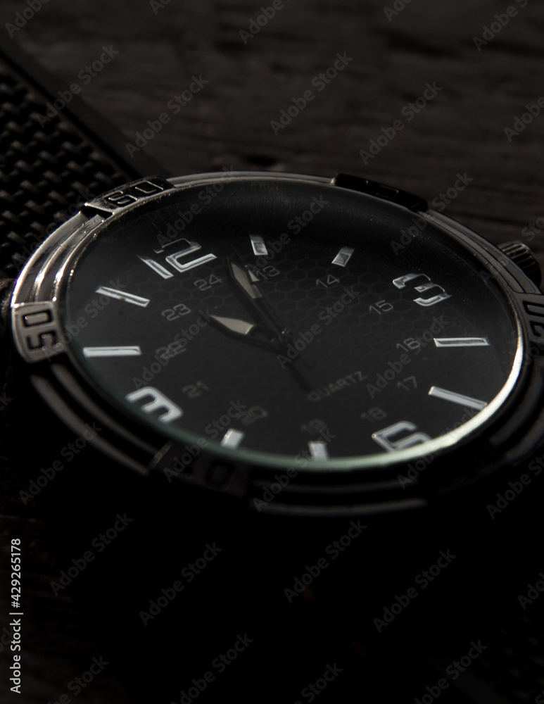 
details of elegant silver watch with black wood background
