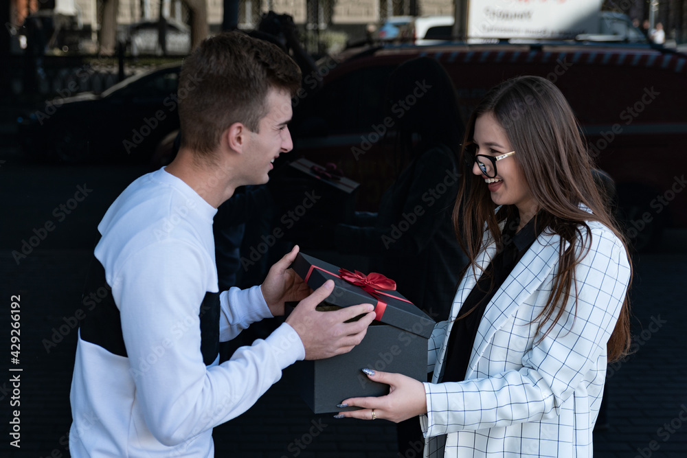 Happy young couple in love with gift. Guy makes gift to his beloved