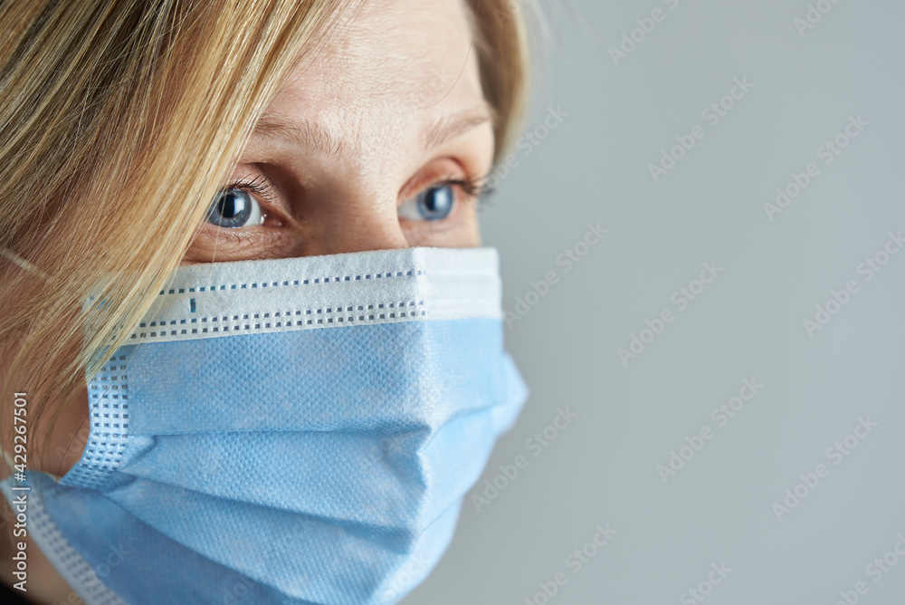 Woman blonde wearing medical face mask on a gray background. Photo with copy space. Woman blonde wearing medical face mask on a gray background. Photo with copy space.