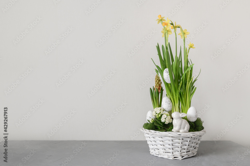 Easter flowers composition with blossom narcissus, hyacinth and organic eggs in white wicker basket. Spring flowering bulbs in a potting. Copy space. Festive greeting card.