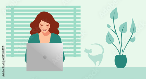 Happy and smiling businesswoman working on her computer surrounded by plants and a cat