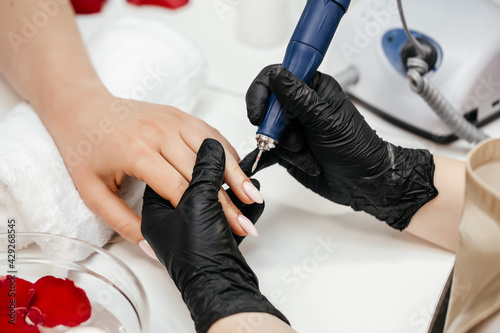 Professional manicure master uses electric machine. hands during manicure. Clipping nails  hand care and nailcare at beauty salon