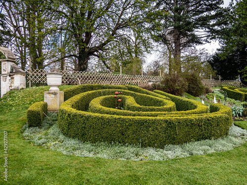A view of the labyrinth from a hedge surrounded by greenery and trees in the garden.