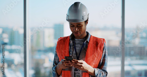 Architect male afro-american engineer working on cponstruction deisgn paperplan of new residential building and using tablet computer manager interface. photo