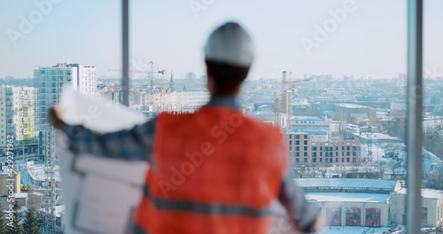 Architect male afro-american engineer working on cponstruction deisgn paperplan of new residential building and using tablet computer manager interface. photo