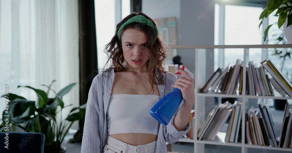 Angry young caucasian woman housewife looking very daring sprinkling water to cool down looking serious to camera exhausted from housework. Angry young caucasian woman housewife looking very daring sprinkling water to cool down looking serious to camera exhausted from housework.