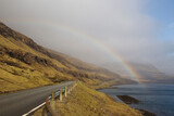Rainbow above the beautiful road between mountains and the sea in Faroe islands which is a part of Denmark