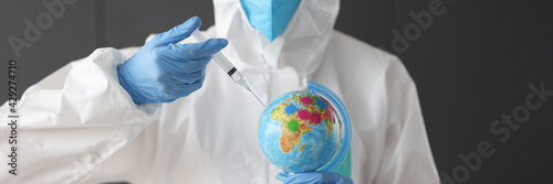 Doctor in anti-plague suit making injection into globe photo