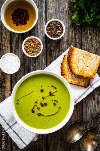 Cream green peas soup on wooden table 
