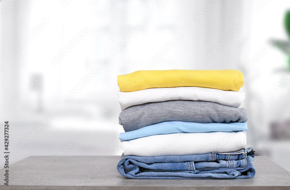 Stack of cotton colorful clothes on table indoors.Stacked apparel.Folded clean clothing. - obrazy, fototapety, plakaty 