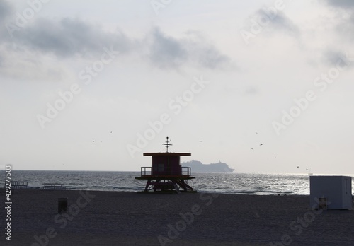 Sunrise horizon at South Beach in the city of Miami Beach Florida with lifeguard tower and a silhouette of a cruise ship in background. Crisis in the tourism industry due to outbreak of coronavirus © Blue