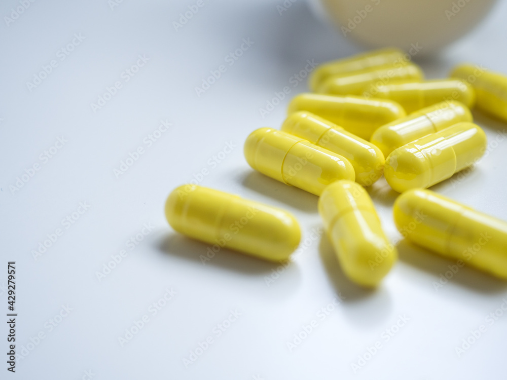 Close up yellow pills with bottle and white background and copy space. Medical concept for sick times Close up yellow pills with bottle and white background and copy space. Medical concept for sick times