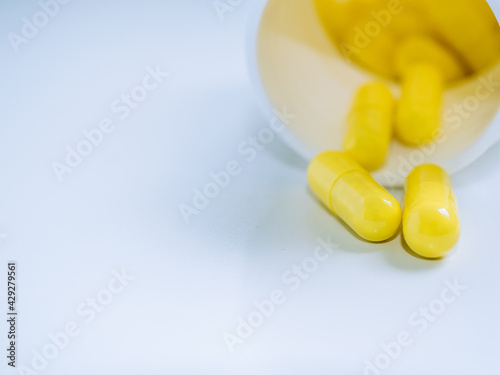 Close up yellow pills with bottle and white background and copy space. Medical concept for sick times