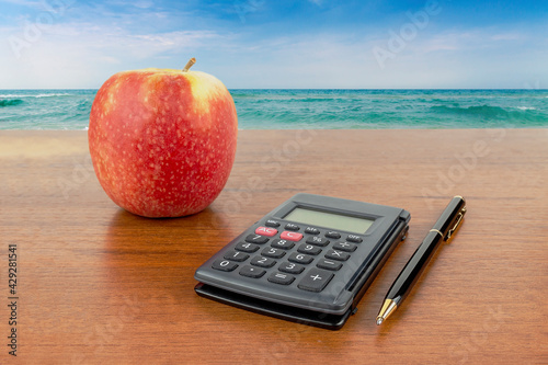 Apple calculator pencil lie on the table against the backdrop of the sea
