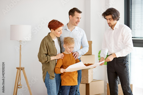 Caucasian family talking with real estate agent while analzying housing plans during meeting