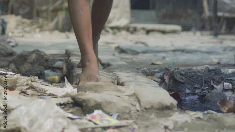 Young Indian poor orphan girl, walking on road with naked dirty feet near garbage, rural village, Stock ビデオ | Adobe Stock