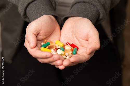Man holding various pills and vitamins