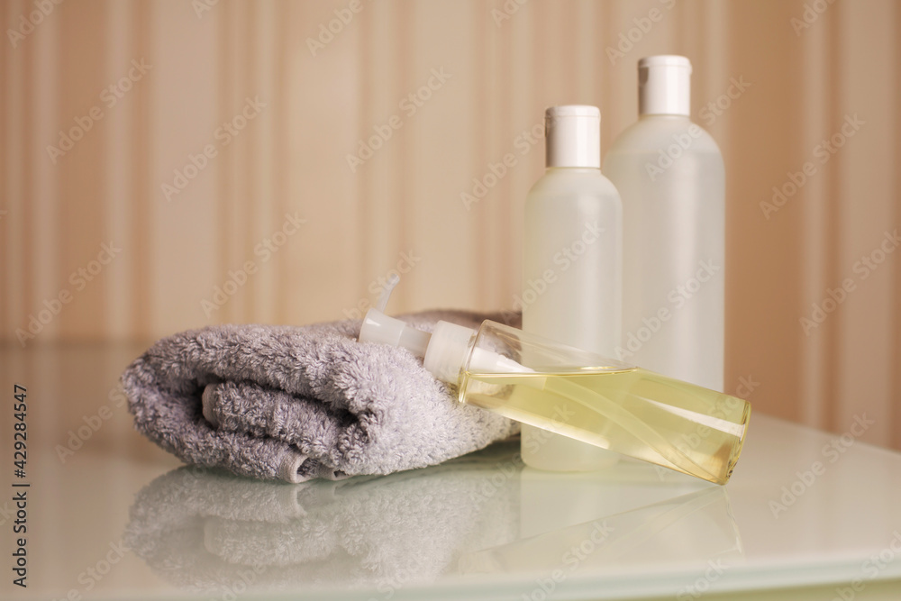 Bottles of shampoo, bath foam and micellar oil with towel