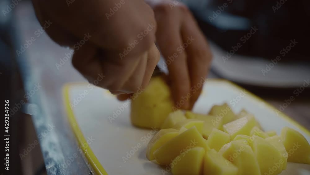 Healthy food. Hands close-up male cuts raw washed potatoes on a cutting board at home in the kitchen. Surprise, help for wife. Vegetarian or vegan lifestyle. Man cooking at home. Cutting vegetables Healthy food. Hands close-up male cuts raw washed potatoes on a cutting board at home in the kitchen. Surprise, help for wife. Vegetarian or vegan lifestyle. Man cooking at home. Cutting vegetables