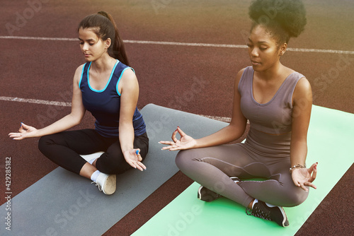 Two female friends meditating while doing yoga in the park. Outdoor Yoga. Lifestyle