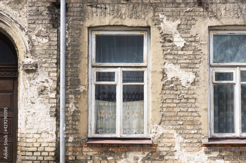 Old ruined building window. Brick wall apartment building background. Post war architecture. Broken old wooden window frame. Historic tenement house background.